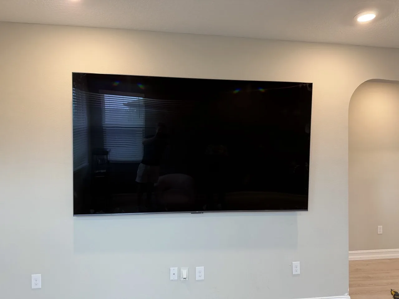 A large flat-screen TV sitting flush against a plain living-room wall with no visible cables running to the outlets below.