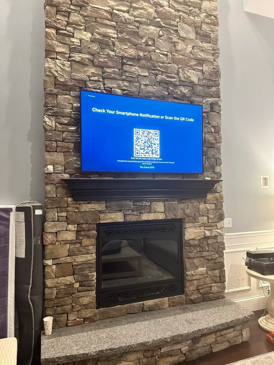 A Frame TV mounted above a stacked-stone fireplace, centered on the chimney breast with no visible cables.