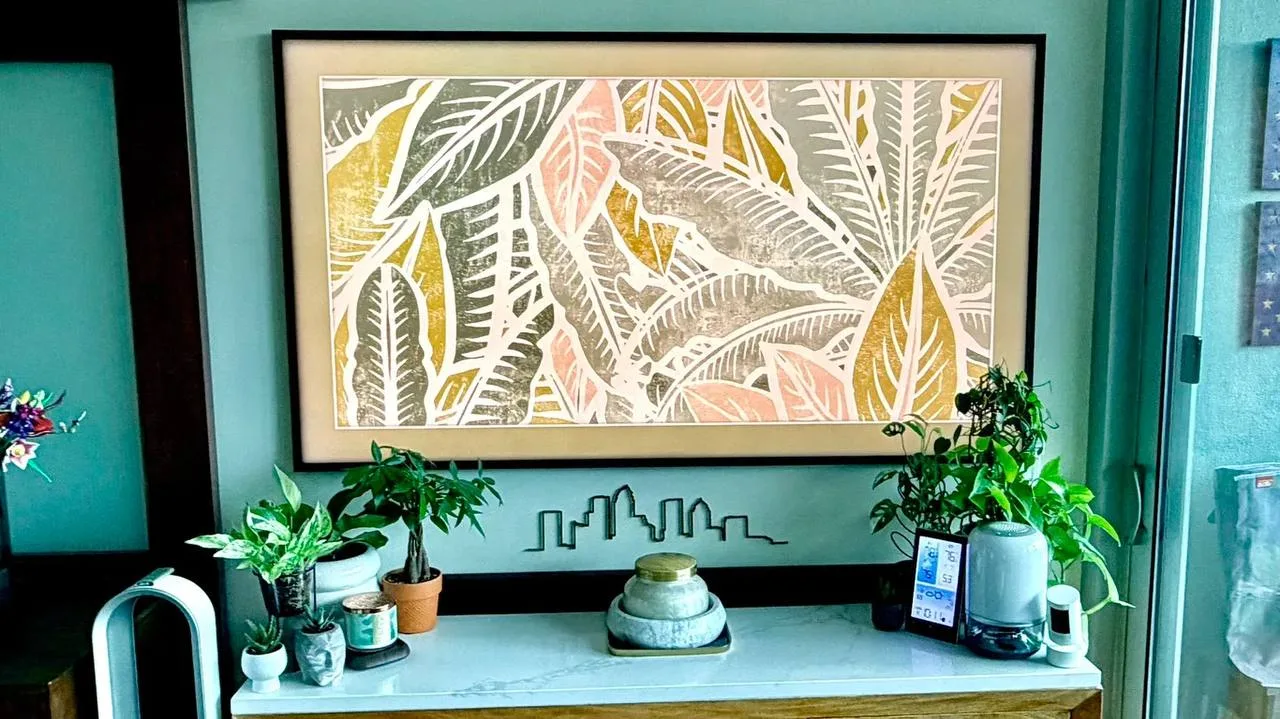 A Frame TV in a black wood frame mounted above a console table for a Florida homeowner, displaying decorative art to match the room.